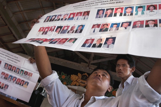 Men examining voting sheets with portraits
