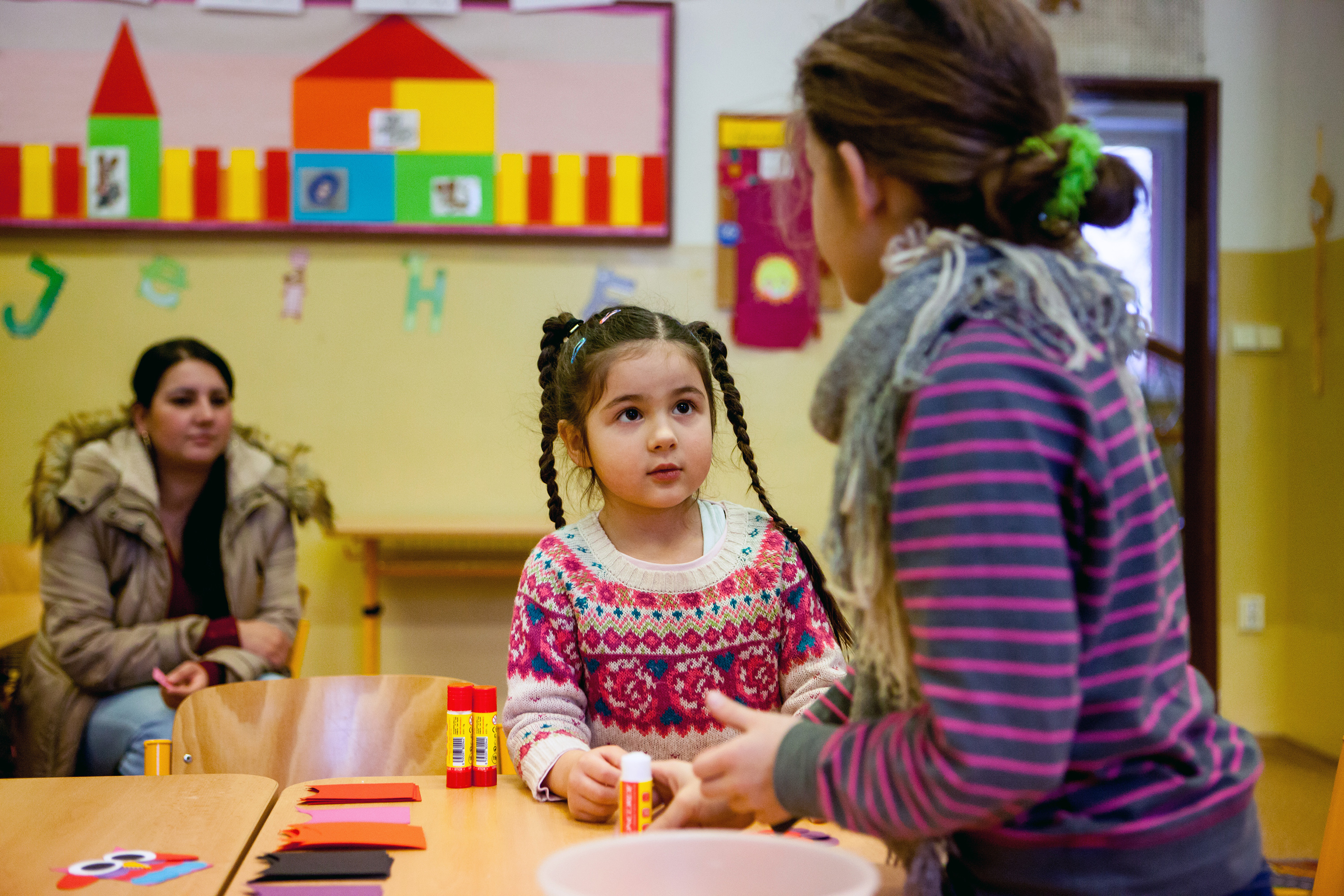 Woman sitting in classroom behind two children at a desk