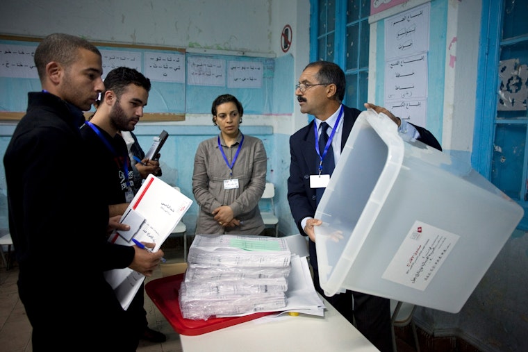 The chief of a polling station in downtown Tunis, Tunisia, displays the ballot box in front of his colleagues and election observers on October 23, 2011. Photo credit: © Zacarias Garcia/EPA/Shutterstock A polling station official in Tunis, Tunisia shows a ballot box to election observers.