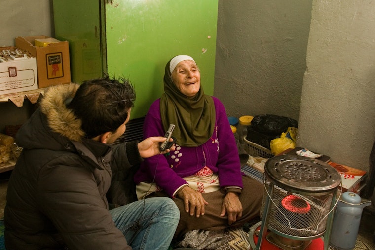 The founder of an online radio news station conducts an interview in Amman, Jordan, on April 11, 2014. Photo credit: © Oraib Toukan A man with a microphone speaks with a woman who is laughing.