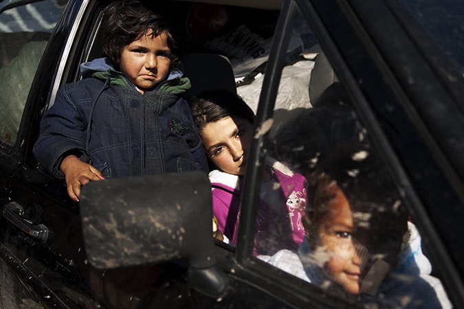 Roma girls wait in their family’s car as city workers pack their belongings. The Belville camp in New Belgrade on the morning of its destruction by the Belgrade city government. Photo credit: © Matt Lutton Girls in a car.