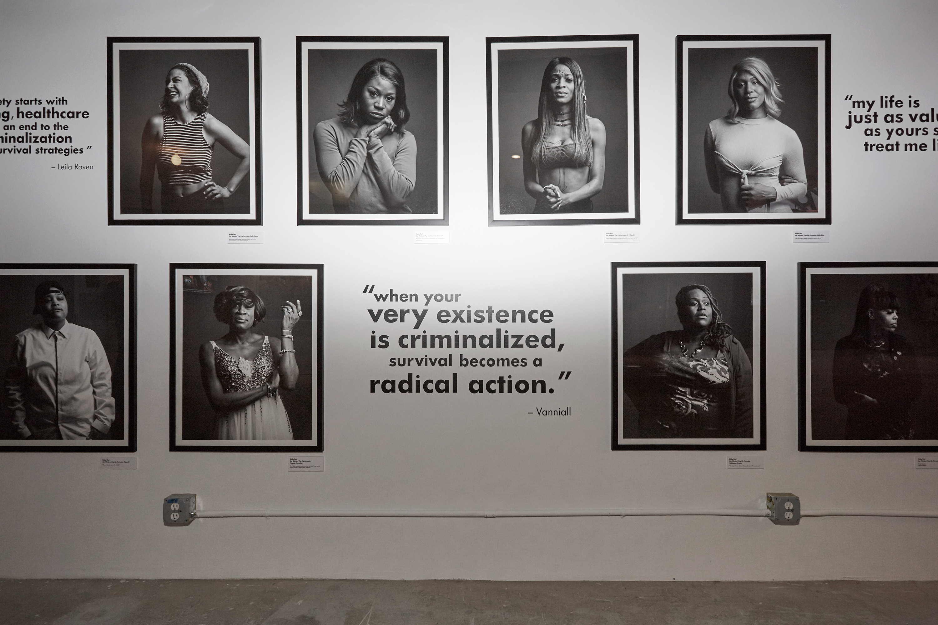 A series of black and white portraits hang on a wall