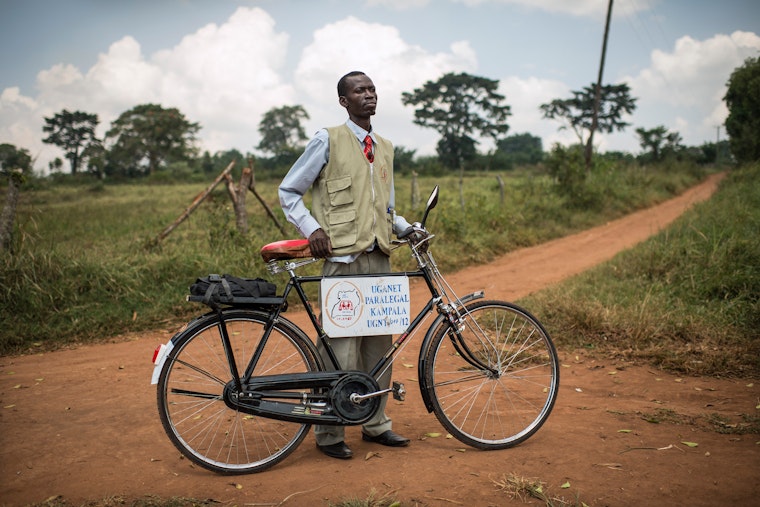 A man stands on the road with his bicycle.