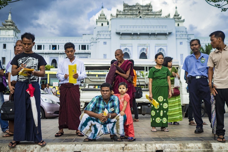 People in front of Yangon’s City Hall listen to speakers at a campaign rally on November 3, 2015. Photo credit: © Jack Kurtz/Newscom People stand on a sidewalk in front of Yangon City Hall building.