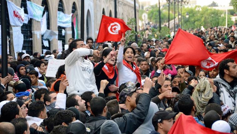 Demonstrators gather in front of the prime minister's office demanding the ouster of cabinet ministers in Tunis, Tunisia, on January 24, 2011. © Kyodo News/Getty A crowd of demonstrators waving flags in the street