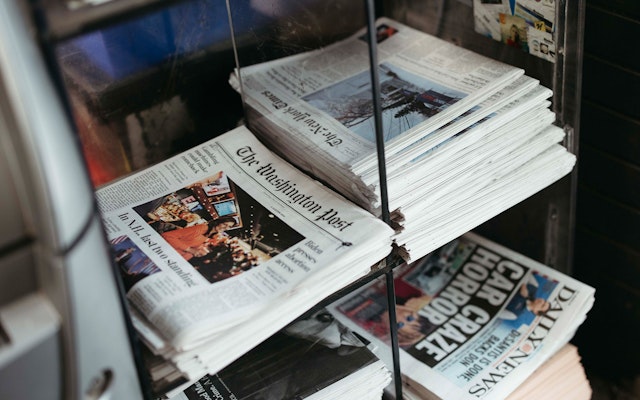 Stacks of newspapers at a newsstand