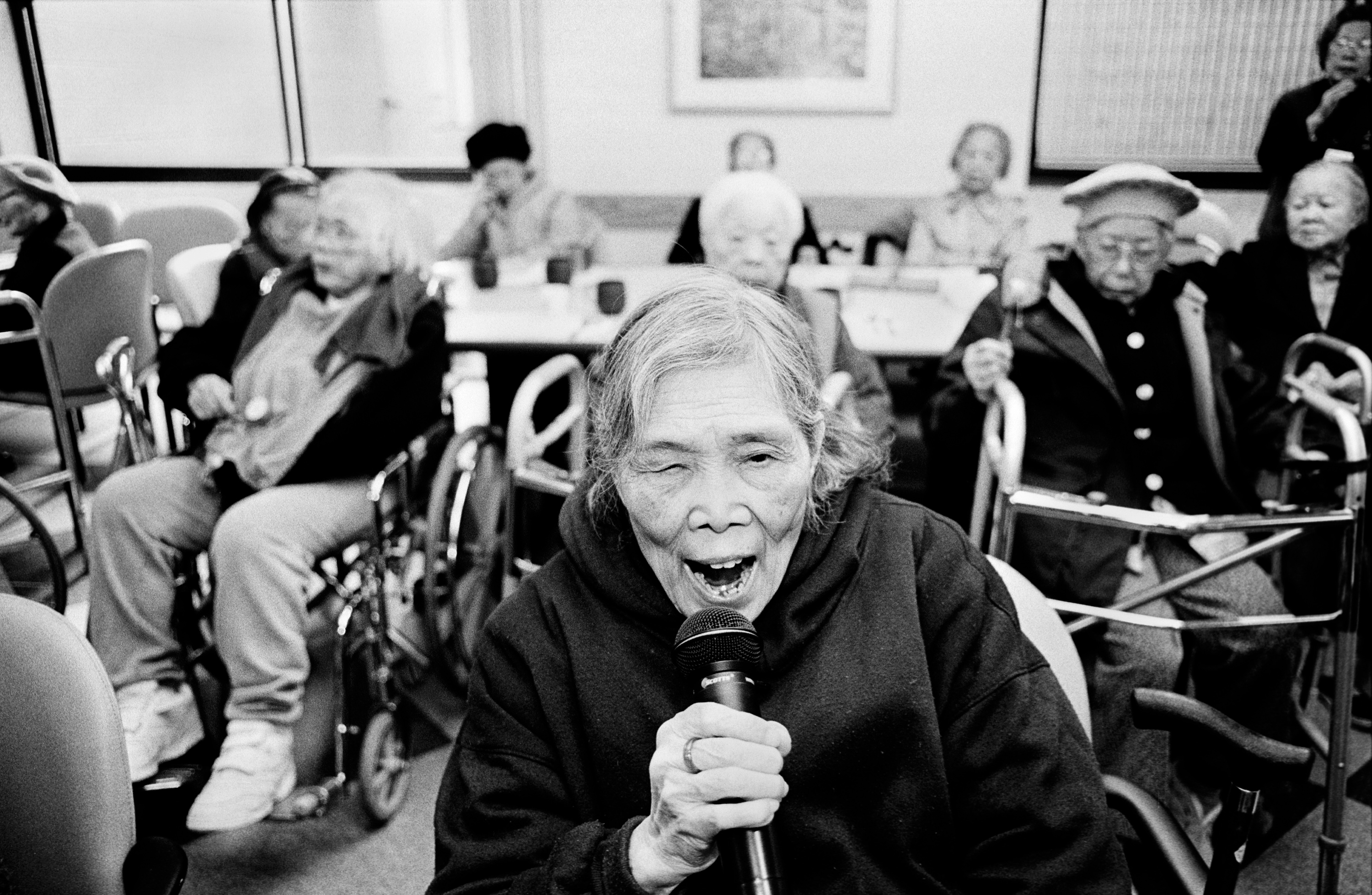 An older woman sings into a microphone