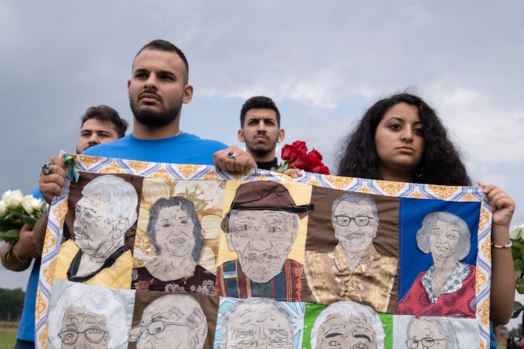 Young people carry a quilt.