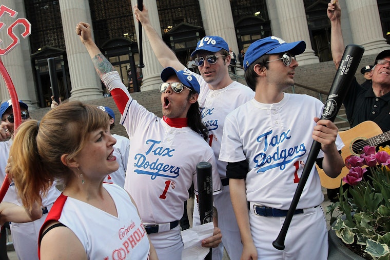 Protesters perform a skit about corporate tax loopholes at a demonstration in New York City, on April 17, 2012. Photo credit: © Justin Sullivan/Getty People in mock baseball uniforms