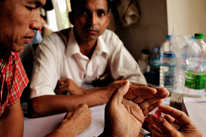 Two men watching a ruby being inspected
