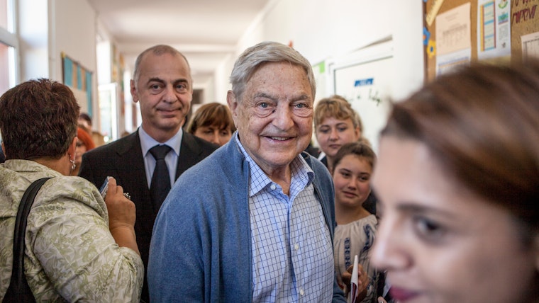 George Soros in a school hallway with a group of people