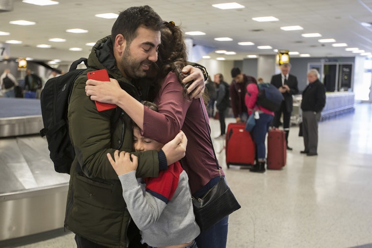 A family hugs at an airport baggage carousel