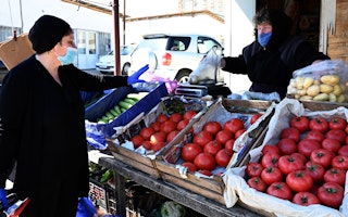 A woman buying vegetables at an outdoor market