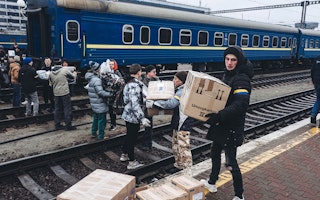 People moving boxes by a train