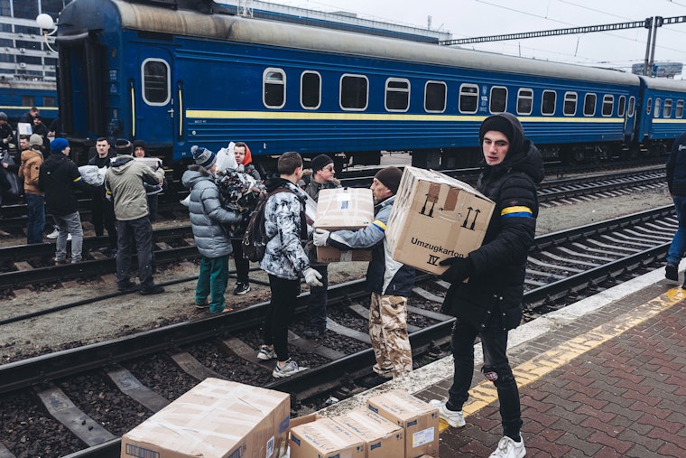 Люди переносять коробки з поїзда