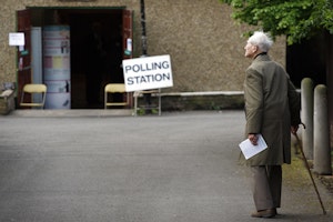 An elderly man walking with a cane towards a polling station