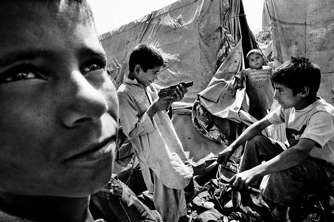 between-suffering-20100225 Boys at refugee camp; boy plays with a gun