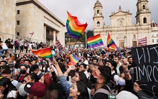 A crowd of people holding rainbow flags