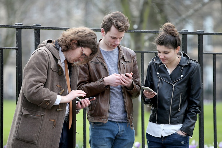 three people looking at their phones
