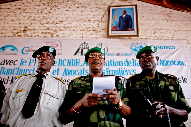 President of the military court reads out sentences for Congolese soldiers accused of rape in Baraka, Democratic Republic of Congo, on February 21, 2011. Photo credit: © Pete Muller/AP Three men stand and one holds a paper.