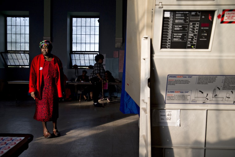 A woman standing by a voting booth