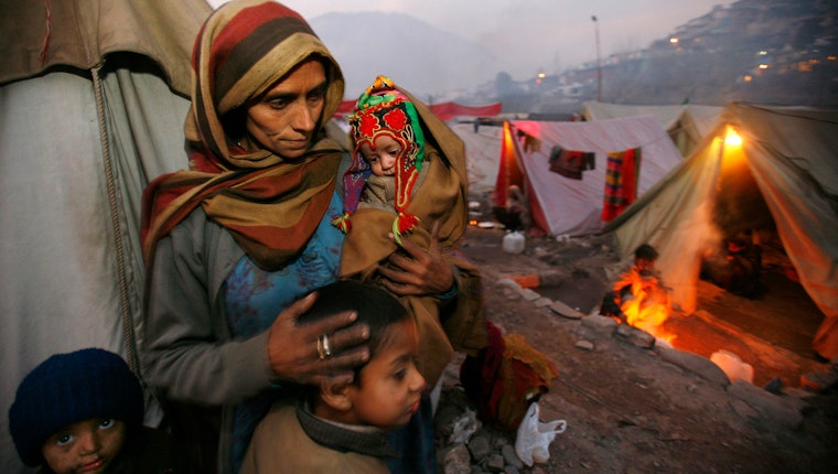 A mother holds her infant daughter in a tented camp in Muzaffarabad, Azad Kashmir, on December 16, 2005. Photo credit: © Paula Bronstein/Getty A woman with several children among tents