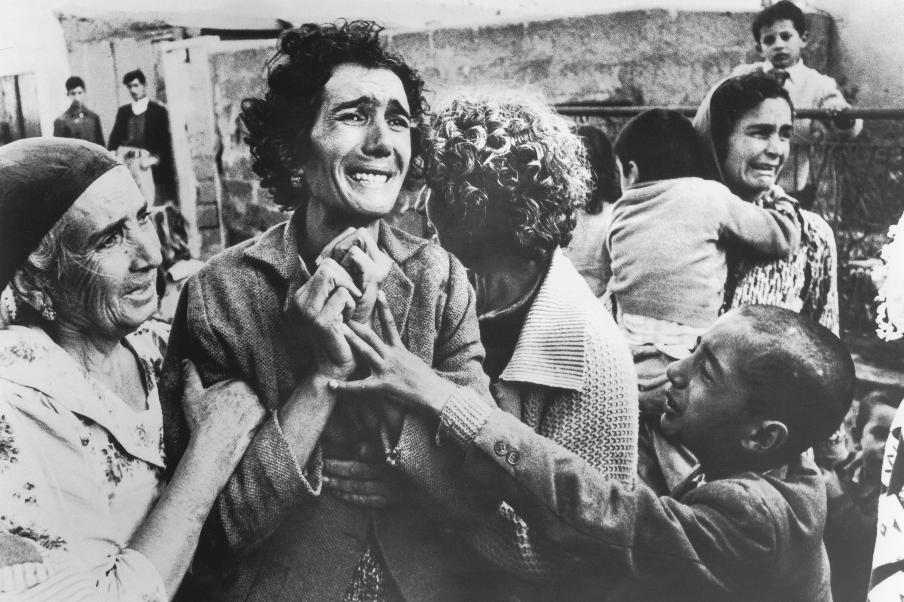 A woman cries and is held by people around her