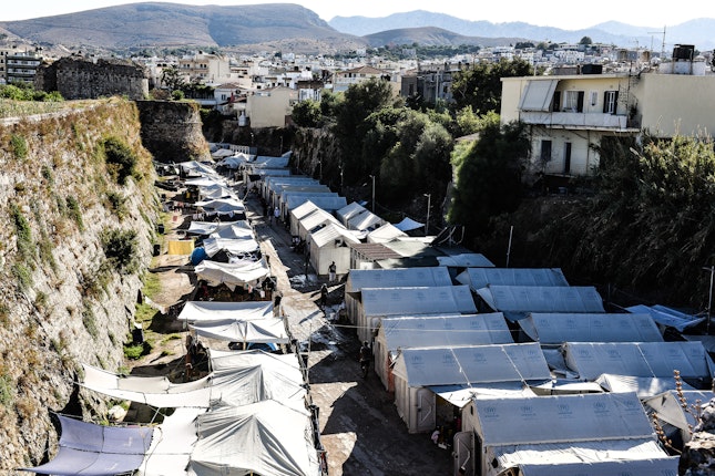 A row of refugee agency tents next to a fortress wall