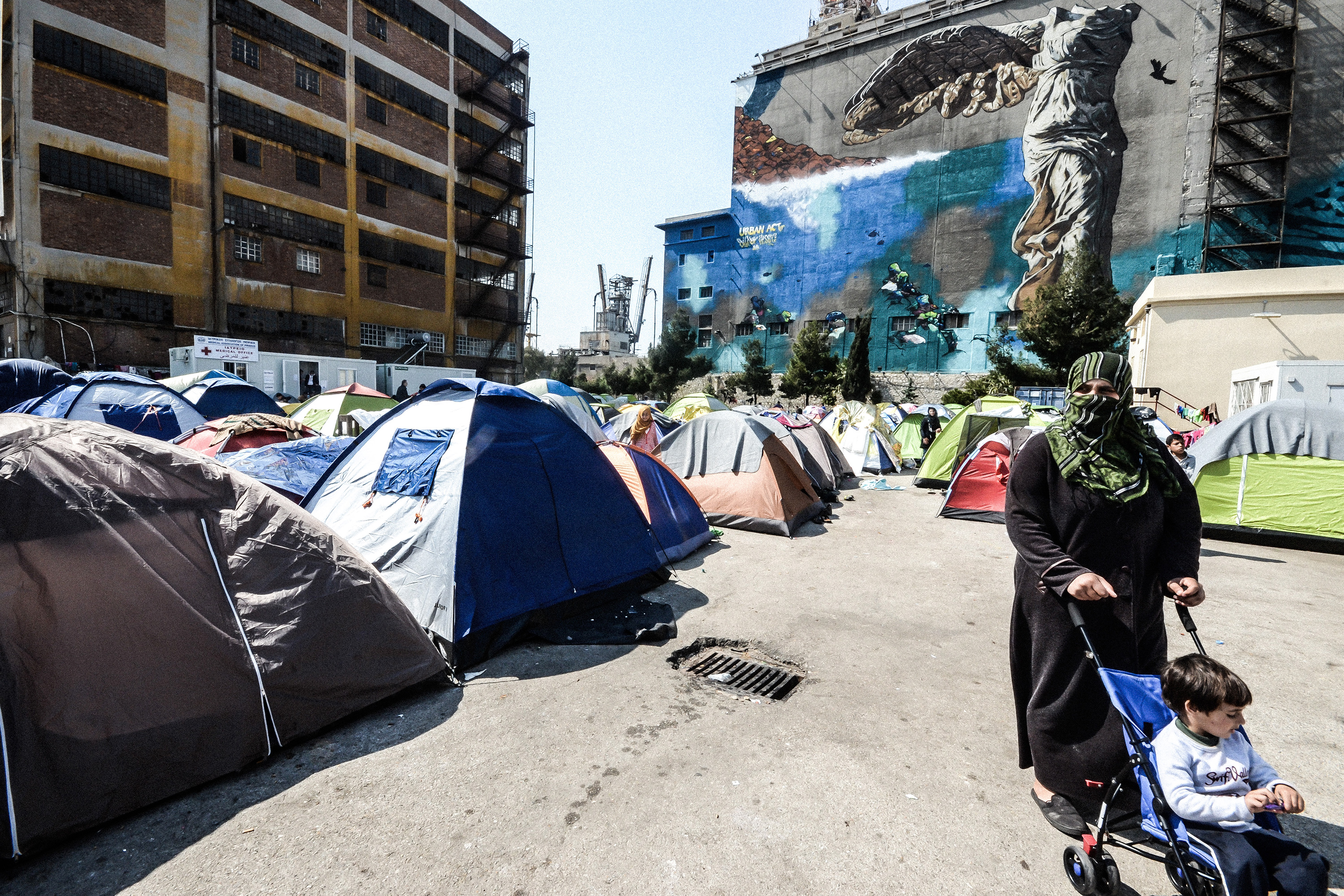 A wman pushing a child in a stroller at a port