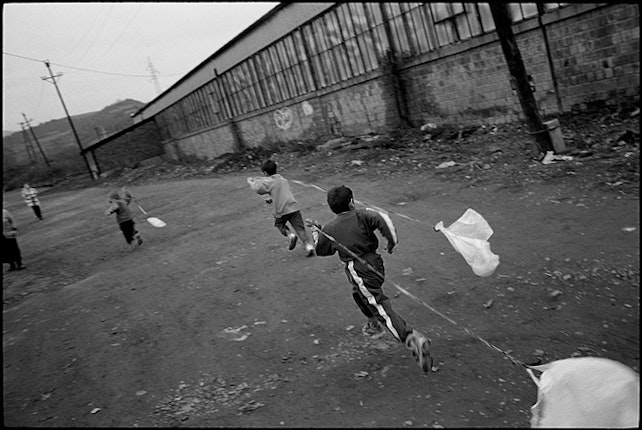 Children in Zitkovac camp fashion kites from simple plastic bags. They are especially vulnerable to exposure to lead residues as they play in the toxic dust. Many of the younger children were born into the camps with various birth defects, a result of their mothers drinking lead-contaminated water during their pregnancy. Photo credit: © Balazs Gardi/VII Network Kids running