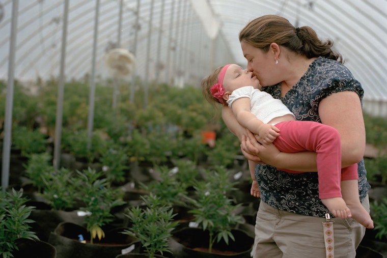 A woman holding her toddler in a greenhouse