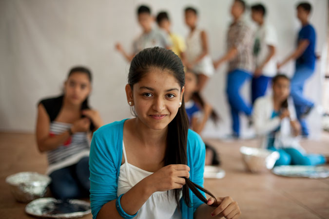 Girls sitting on the floor holding their hair.