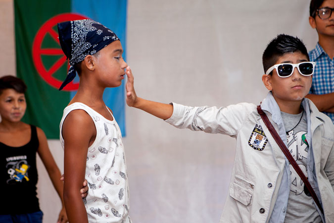 Boy wearing sunglasses holds his hand out to another boy's face.
