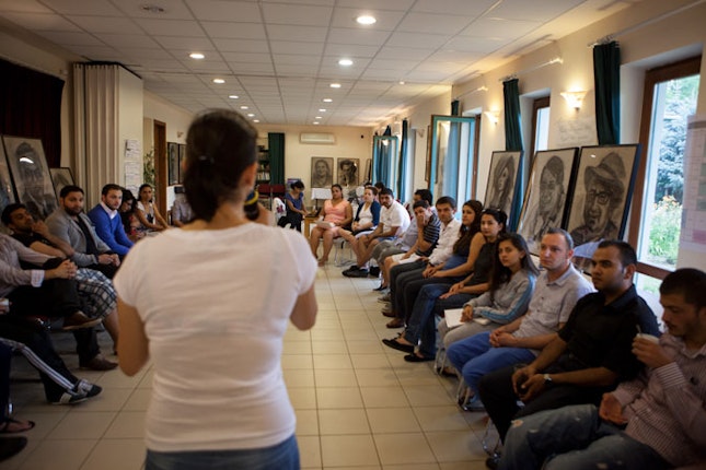 Woman holding microphone, speaking to a group of Barvalipe participants.