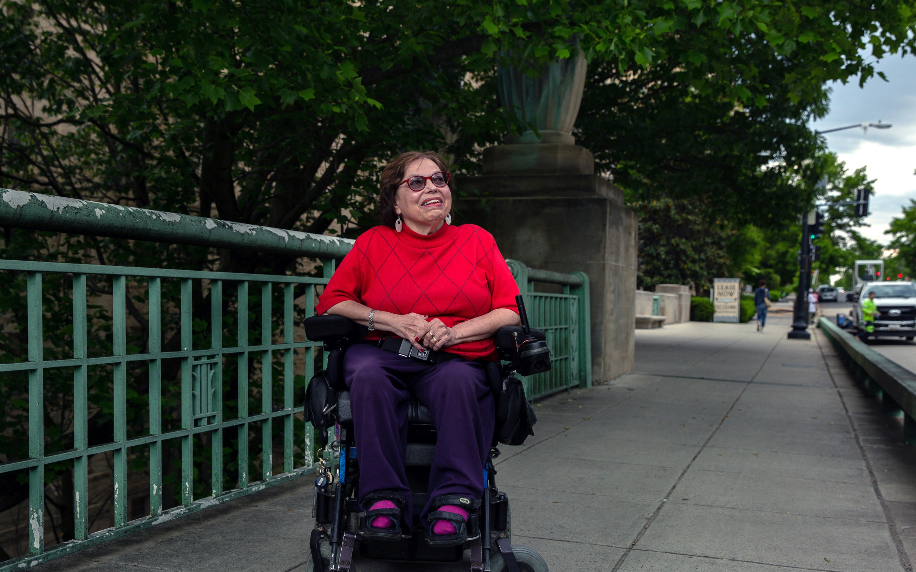 Judith Heumann sitting in a wheelchair on a bridge