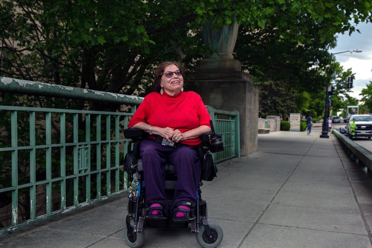 Judith Heumann sitting in a wheelchair on a bridge
