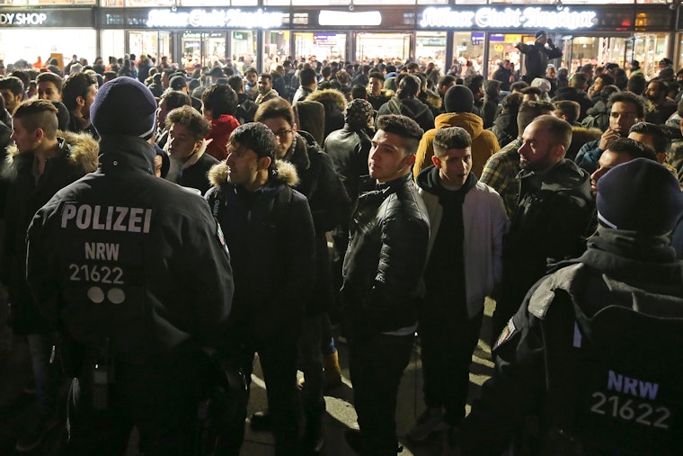 Police hold a group of men in front of the main railway station in Cologne, Germany, on December 31, 2016. Photo credit: © Maja Hitij/Getty A large group of people stand in a plaza