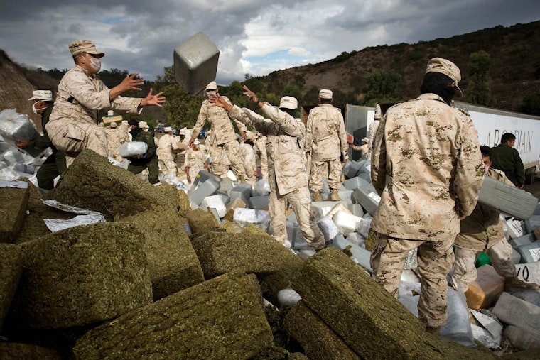 Soldiers gathering bales of marijuana