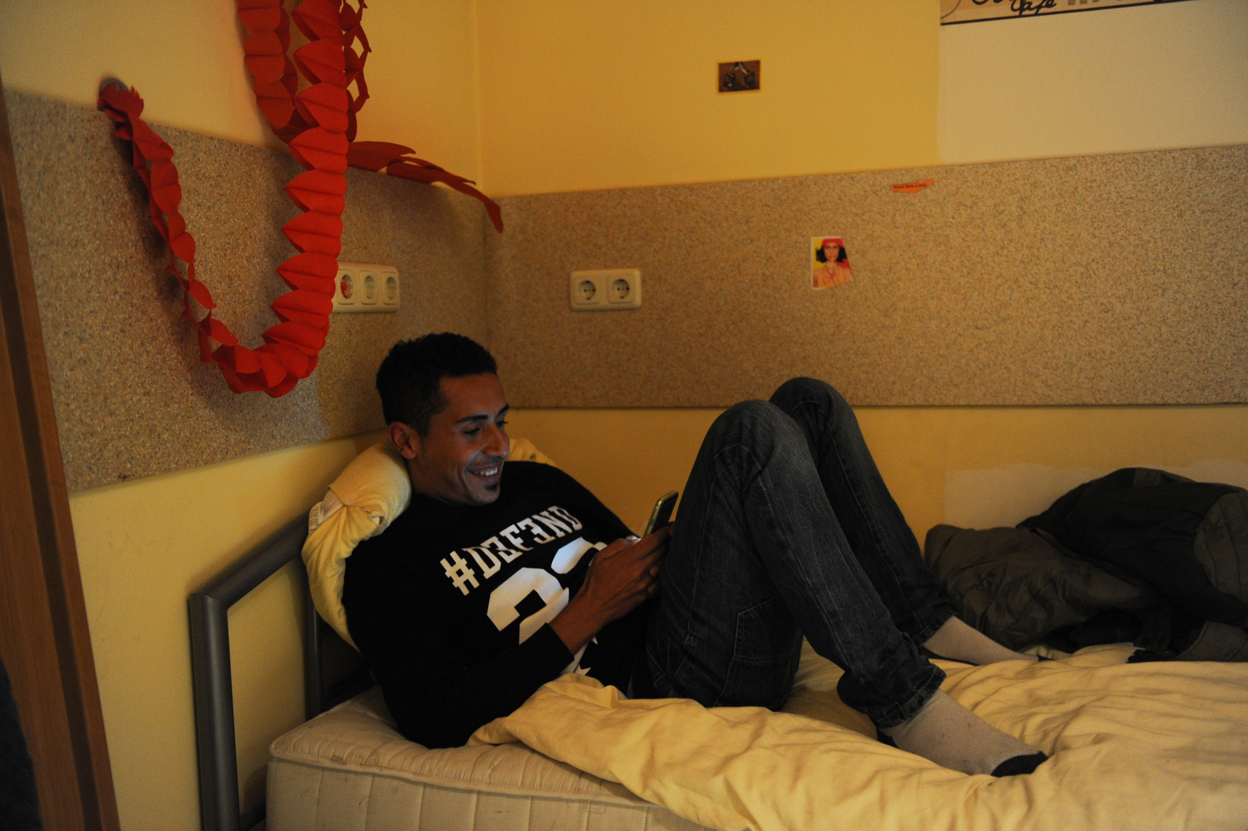 Man on a smart phone reclining on a bed
