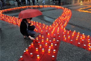 A red ribbon lined with candles on pavement