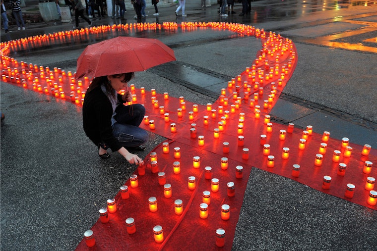 A red ribbon lined with candles on pavement