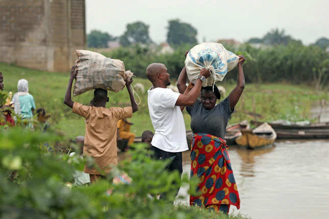 Farmers prepare to transport produce to a market in Benue State, Nigeria, on August 12, 2021. © Kola Sulaimon/AFP/Getty People carrying bags of produce along a river