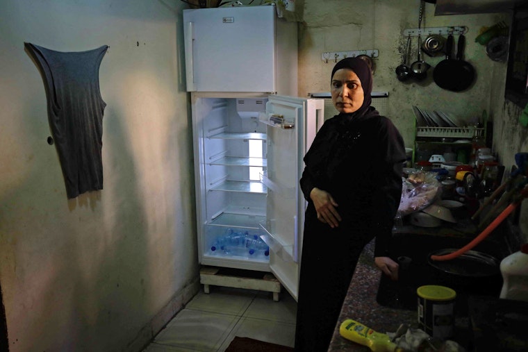 A Lebanese woman stands next to an empty refrigerator in her apartment in Tripoli, Lebanon, on June 17, 2020. Photo credit: © Ibrahim Chalhoub/AFP/Getty A woman stands in front of an empty refrigerator.