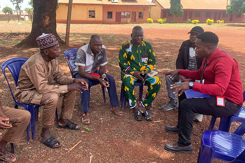 A group of six men sit in a semicircle