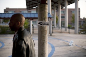 A man walking past a “Voting” sign