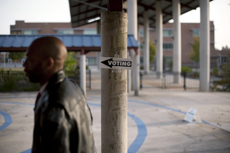 A man enters a school to cast his vote on November 4, 2014, in Charlotte, North Carolina. Photo credit: © Davis Turner/Getty A man walking past a “Voting” sign