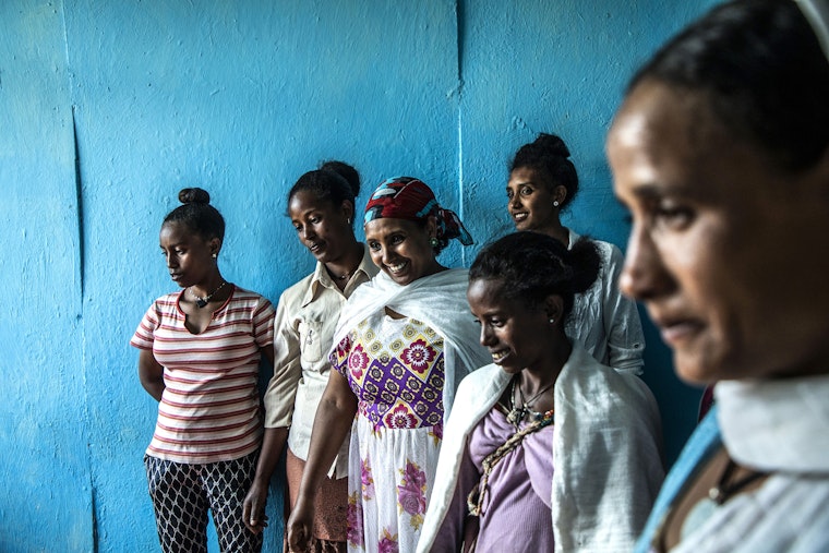 Domestic workers attend a training session in Debre Marcos, Ethiopia, on October 29, 2019. Photo credit: © Stefano Dal Pozzolo/contrasto/Redux A group of smiling women near a blue wall