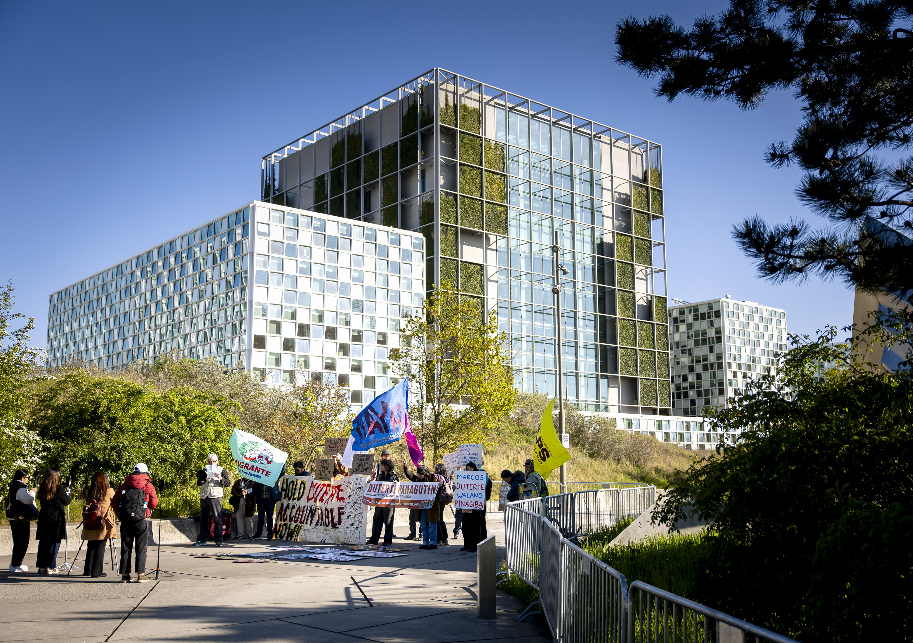 People stand in front of a mirrored building holding placards
