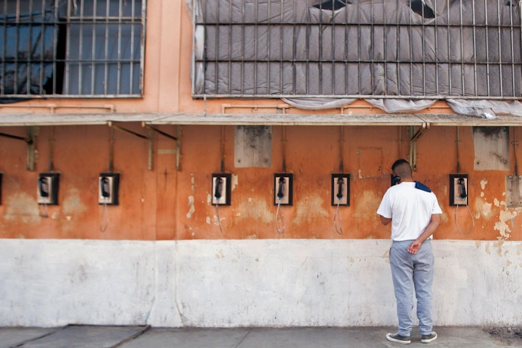 An inmate speaks on the phone against the wall