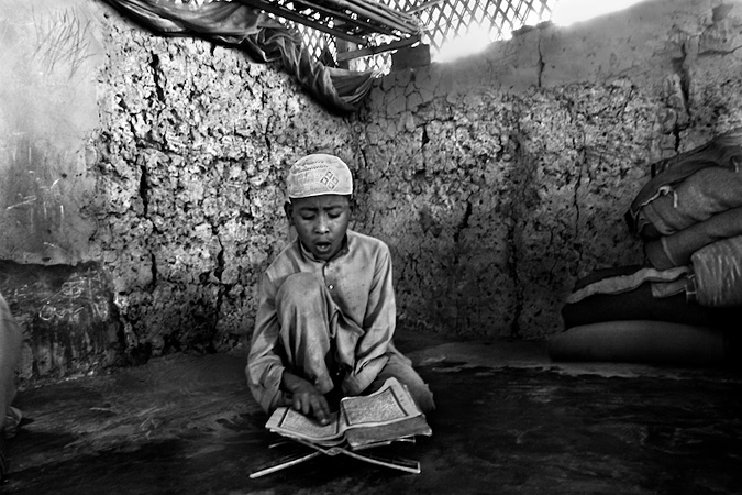 Boy sitting, reading the Qur'an